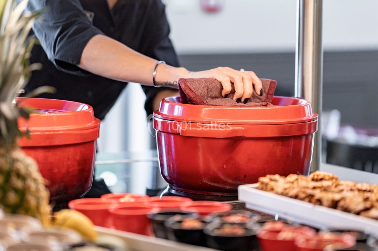 Une personne essuie un couvercle rouge avec un chiffon dans un espace de restauration.