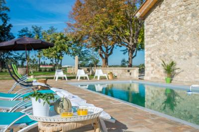 Chambre lumineuse avec lit double, fauteuil beige, fenêtre ouverte sur un paysage et décoration murale en osier.