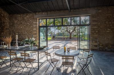 Chambre lumineuse avec lit double, bureau noir, lampe en rotin et fenêtre ouverte donnant sur un arbre.