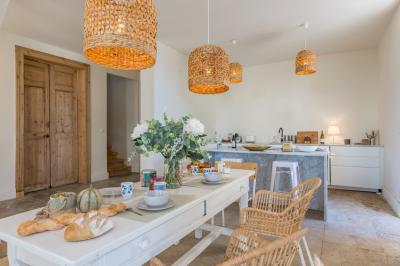 Chambre lumineuse avec lit double, bureau noir, lampe en rotin et fenêtre ouverte donnant sur un arbre.