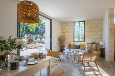 Chambre lumineuse avec lit double, bureau noir, lampe en rotin et fenêtre ouverte donnant sur un arbre.