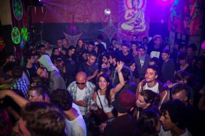 Groupe de personnes discutant et partageant un moment convivial en extérieur, éclairé par une lumière nocturne.