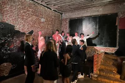 Groupe de personnes discutant et partageant un moment convivial en extérieur, éclairé par une lumière nocturne.