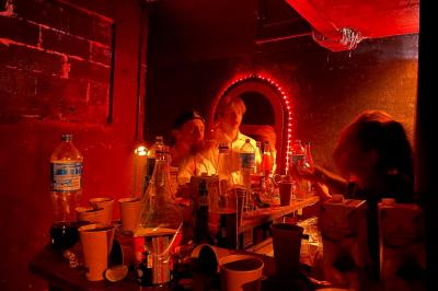 Groupe de personnes discutant et partageant un moment convivial en extérieur, éclairé par une lumière nocturne.