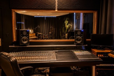 Salle sombre avec éclairage rouge et bleu, une estrade avec équipement audio et un tapis mural en arrière-plan.