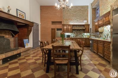 Piscine rectangulaire entourée de dalles et pelouse, avec un grand arbre en arrière-plan sous un ciel dégagé.
