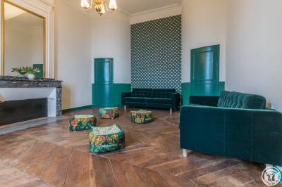 Piscine rectangulaire entourée de dalles et pelouse, avec un grand arbre en arrière-plan sous un ciel dégagé.