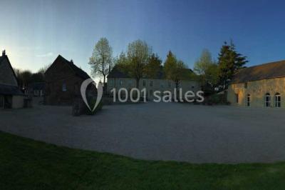 Vue aérienne d'un domaine rural avec bâtiments en pierre, cour centrale, champs, étang et arbres environnants.