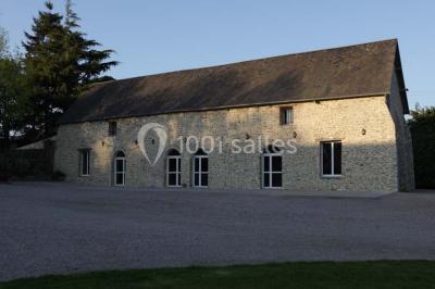 Vue aérienne d'un domaine rural avec bâtiments en pierre, cour centrale, champs, étang et arbres environnants.