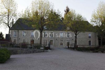 Vue aérienne d'un domaine rural avec bâtiments en pierre, cour centrale, champs, étang et arbres environnants.