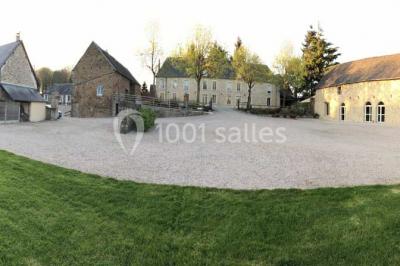 Vue aérienne d'un domaine rural avec bâtiments en pierre, cour centrale, champs, étang et arbres environnants.
