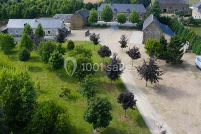 Vue aérienne d'un domaine rural avec bâtiments en pierre, cour centrale, champs, étang et arbres environnants.
