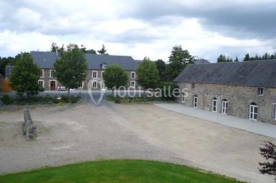 Vue aérienne d'un domaine rural avec bâtiments en pierre, cour centrale, champs, étang et arbres environnants.