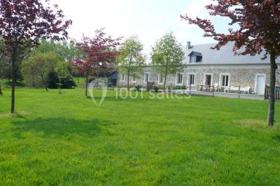 Vue aérienne d'un domaine rural avec bâtiments en pierre, cour centrale, champs, étang et arbres environnants.