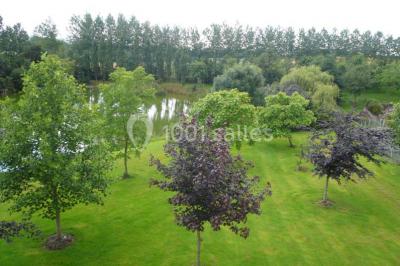 Vue aérienne d'un domaine rural avec bâtiments en pierre, cour centrale, champs, étang et arbres environnants.