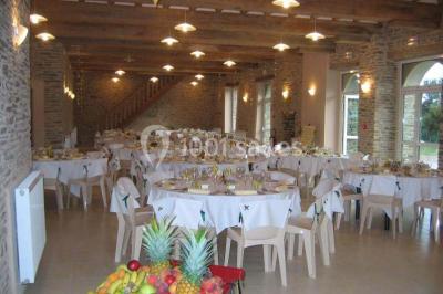 Vue aérienne d'un domaine rural avec bâtiments en pierre, cour centrale, champs, étang et arbres environnants.