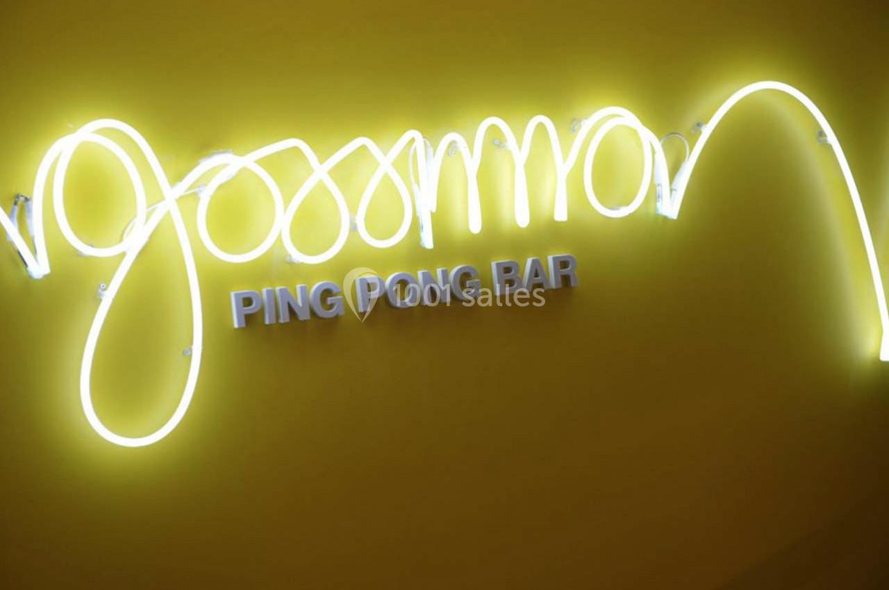 Enseigne lumineuse jaune avec le texte ’Ping Pong Bar’ en lettres blanches sur un mur de la même couleur.