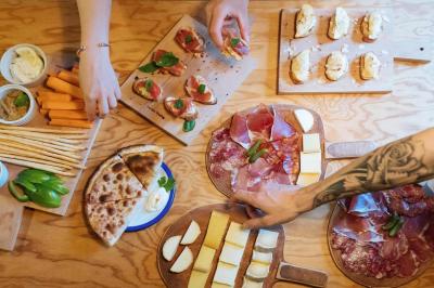 Tranches de pain garnies de légumes grillés, fromage et feuilles de basilic, présentées sur une planche en bois.