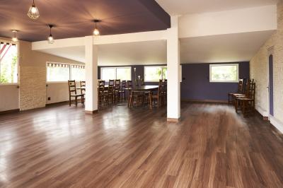 Salle de réception décorée pour un événement, avec tables rondes dressées et un écran de projection allumé.