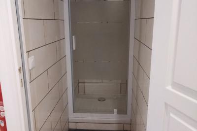 Salle de réception décorée pour un événement, avec tables rondes dressées et un écran de projection allumé.