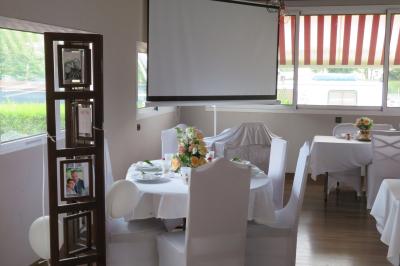 Salle de réception décorée pour un événement, avec tables rondes dressées et un écran de projection allumé.