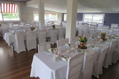 Salle de réception décorée pour un événement, avec tables rondes dressées et un écran de projection allumé.