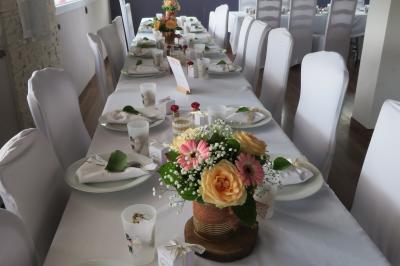 Salle de réception décorée pour un événement, avec tables rondes dressées et un écran de projection allumé.