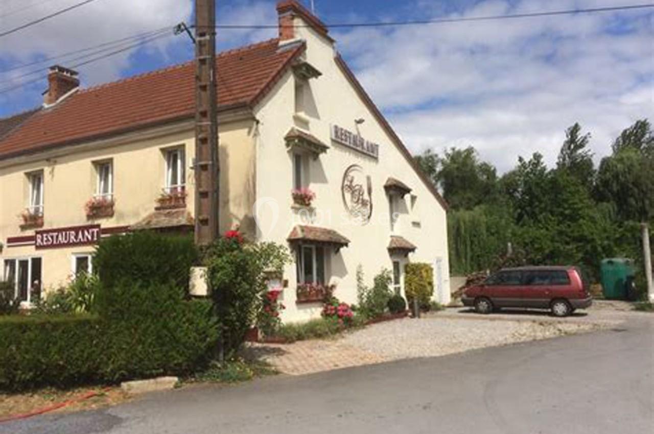 Façade d'un restaurant traditionnel avec des volets rouges, des fleurs en façade et une voiture garée devant.