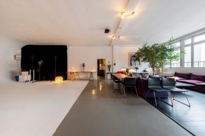 Salle avec des tables et chaises noires disposées en U, projection d’un paon coloré sur un mur blanc, rideaux noirs à droite.