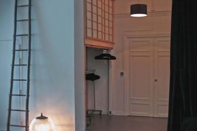 Salle avec des tables et chaises noires disposées en U, projection d’un paon coloré sur un mur blanc, rideaux noirs à droite.