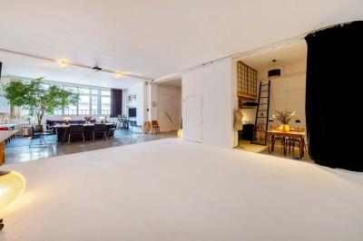 Salle avec des tables et chaises noires disposées en U, projection d’un paon coloré sur un mur blanc, rideaux noirs à droite.