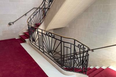 Salle avec des tables et chaises noires disposées en U, projection d’un paon coloré sur un mur blanc, rideaux noirs à droite.