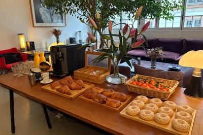 Salle avec des tables et chaises noires disposées en U, projection d’un paon coloré sur un mur blanc, rideaux noirs à droite.