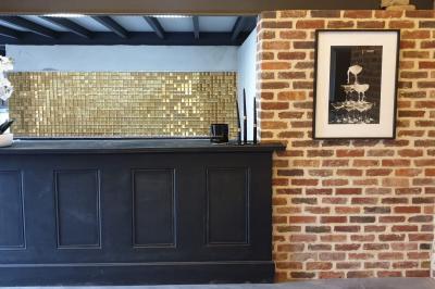 Photographie en noir et blanc d'un couple s'embrassant, la femme en robe de mariée, devant une structure en bois.