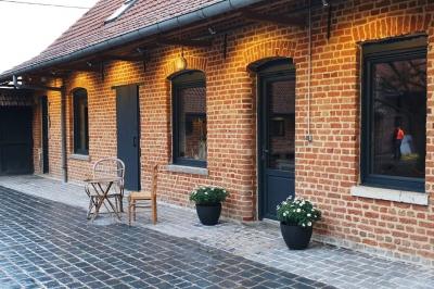 Photographie en noir et blanc d'un couple s'embrassant, la femme en robe de mariée, devant une structure en bois.