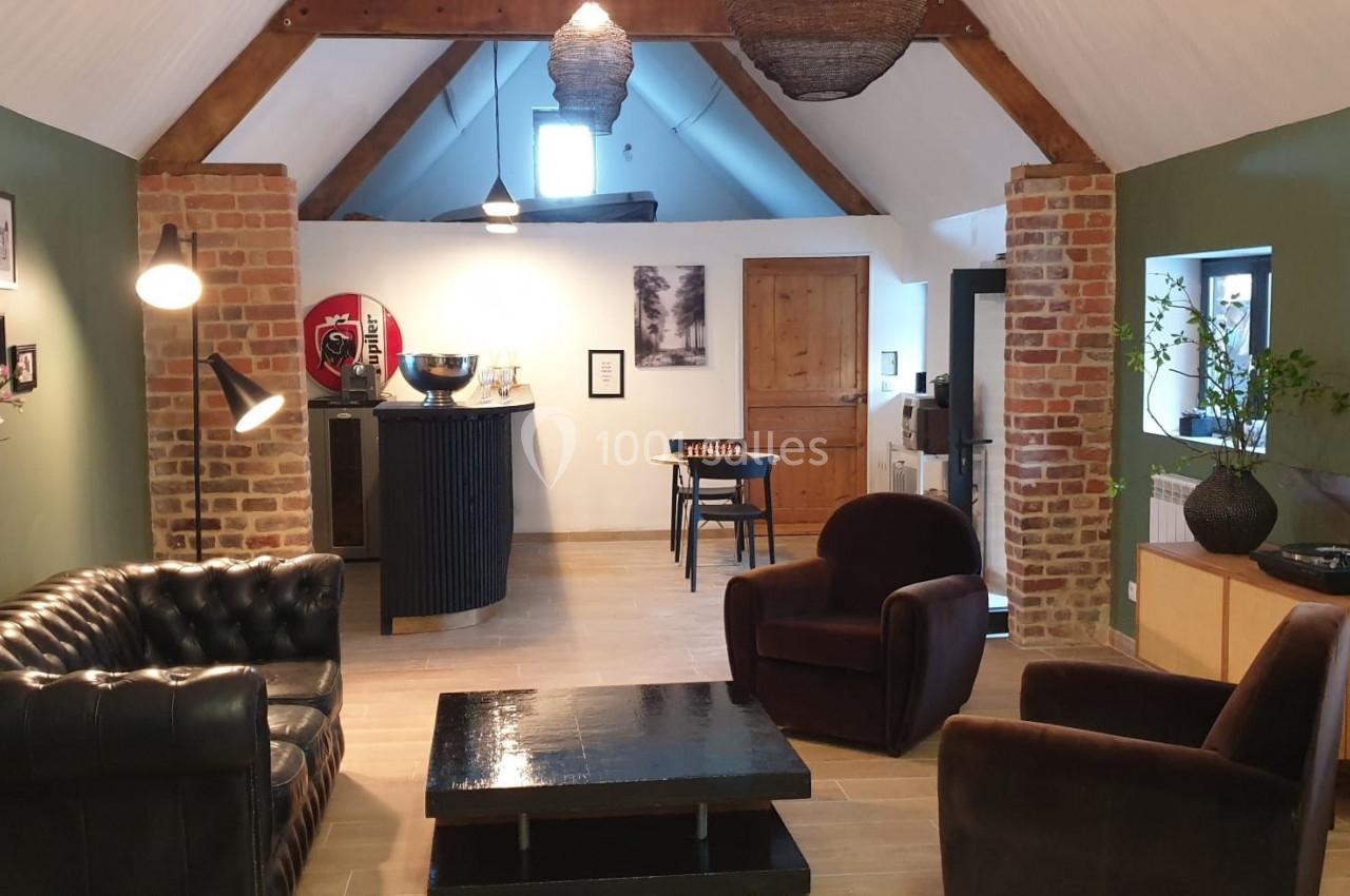 Salon chaleureux avec murs en briques et verts, mobilier en cuir et bois, éclairage doux et décoration moderne.