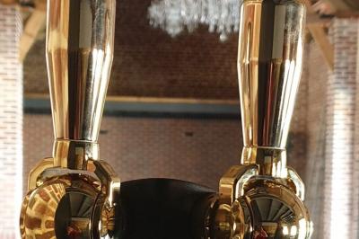 Photographie en noir et blanc d'un couple s'embrassant, la femme en robe de mariée, devant une structure en bois.