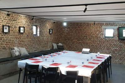 Photographie en noir et blanc d'un couple s'embrassant, la femme en robe de mariée, devant une structure en bois.