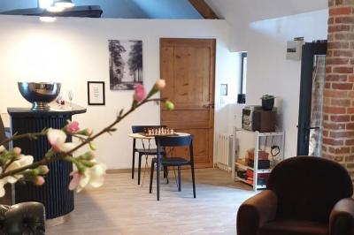 Photographie en noir et blanc d'un couple s'embrassant, la femme en robe de mariée, devant une structure en bois.
