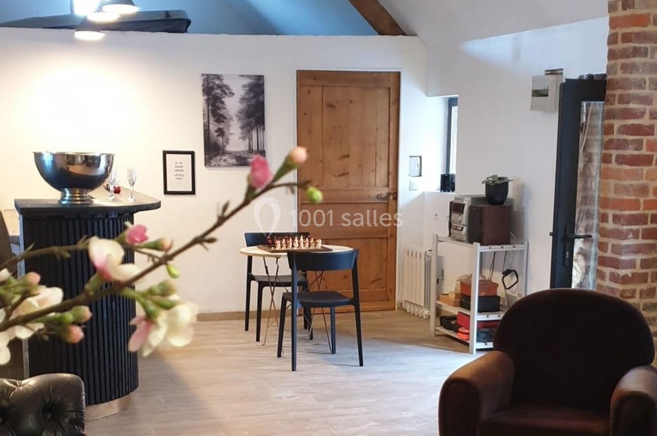 Salle lumineuse avec mobilier moderne, table avec échiquier, mur en briques et décoration minimaliste.