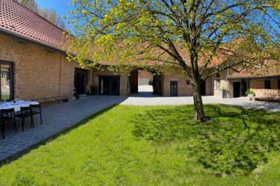 Photographie en noir et blanc d'un couple s'embrassant, la femme en robe de mariée, devant une structure en bois.