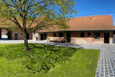Photographie en noir et blanc d'un couple s'embrassant, la femme en robe de mariée, devant une structure en bois.