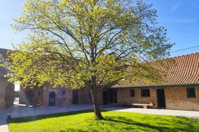 Photographie en noir et blanc d'un couple s'embrassant, la femme en robe de mariée, devant une structure en bois.