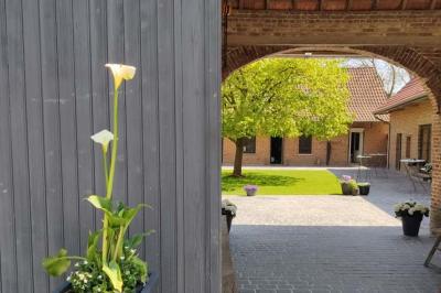 Photographie en noir et blanc d'un couple s'embrassant, la femme en robe de mariée, devant une structure en bois.
