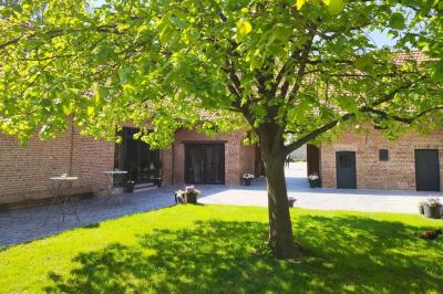 Photographie en noir et blanc d'un couple s'embrassant, la femme en robe de mariée, devant une structure en bois.