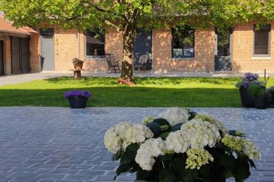 Photographie en noir et blanc d'un couple s'embrassant, la femme en robe de mariée, devant une structure en bois.