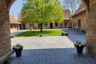 Photographie en noir et blanc d'un couple s'embrassant, la femme en robe de mariée, devant une structure en bois.