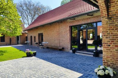 Photographie en noir et blanc d'un couple s'embrassant, la femme en robe de mariée, devant une structure en bois.