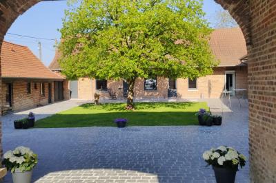 Photographie en noir et blanc d'un couple s'embrassant, la femme en robe de mariée, devant une structure en bois.