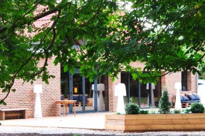 Photographie en noir et blanc d'un couple s'embrassant, la femme en robe de mariée, devant une structure en bois.